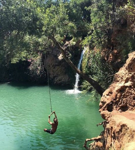 Swinging from rope swing at Pego do Inferno in Tavira