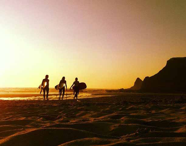 Odeceixe surf sunset surfers walking along the beach at sunset